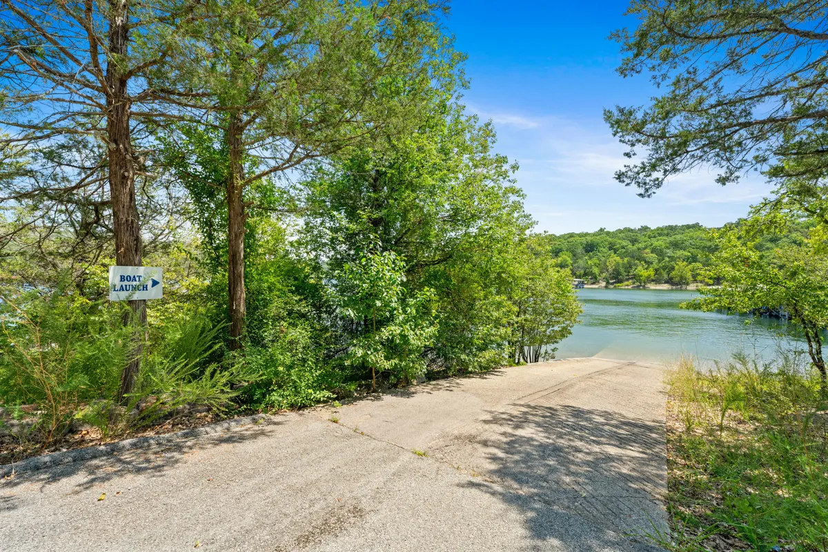 A clear view of a boat launch area, with a concrete ramp leading to the water, surrounded by trees. A sign marks the boat launch, making it easy to identify for guests eager to take advantage of the private boat slip and trailer parking.