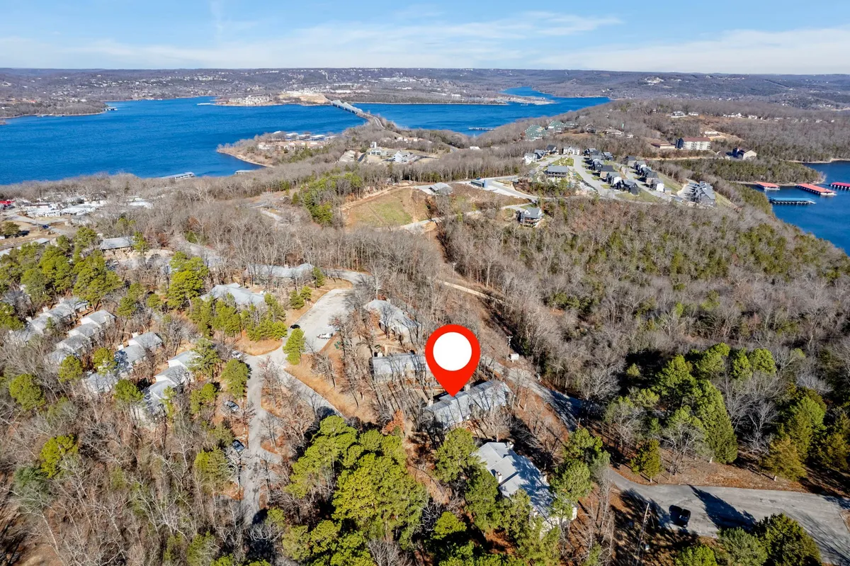 A peaceful panorama showing the lake bordered by wooded areas and residential buildings, with visible roads inviting exploration. The landscape highlights opportunities for hiking, fishing, boating, and observing local wildlife, underscoring the natural beauty of the Ozarks.