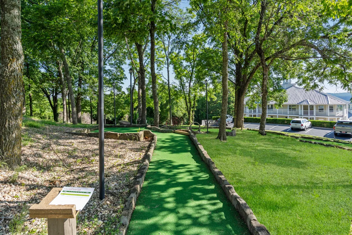 A playful mini-golf course set amidst lush greenery and clear signage, inviting guests to enjoy leisure activities while surrounded by nature. The setting is relaxed and welcoming, ideal for couples or small groups seeking gentle recreation.