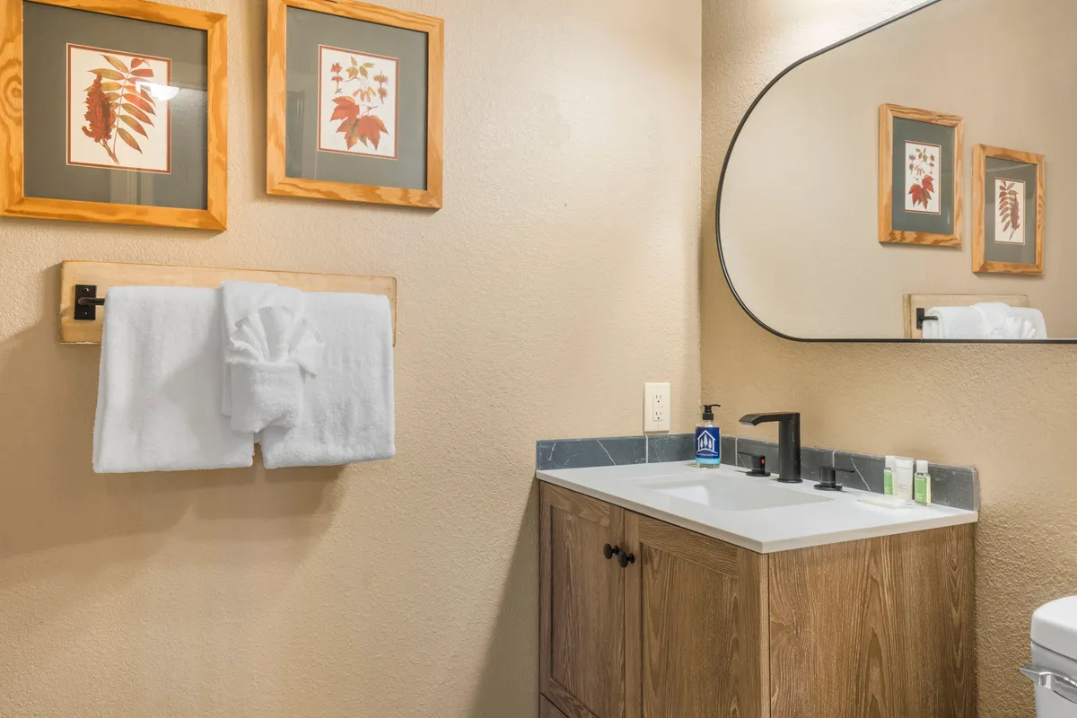A calm and refreshing bathroom featuring a clean vanity with sink, plush towels, and soothing artwork. The arrangement highlights a bright, functional, and serene environment ideal for self-care and relaxation.